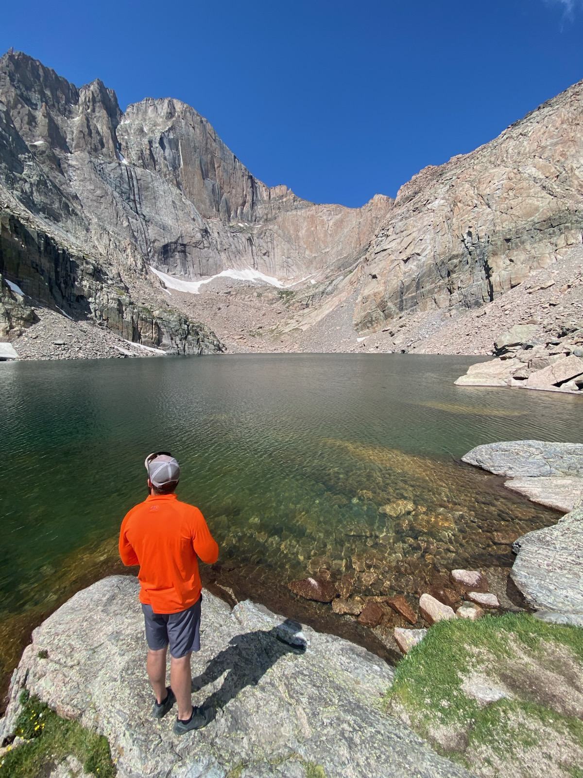 Image of person looking into the distance at an alpine lake at the base of a mountain