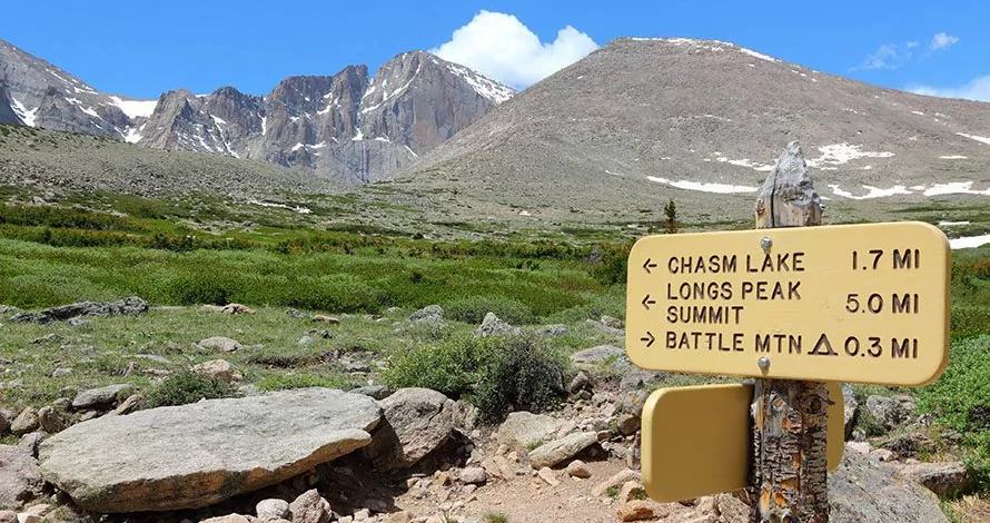 Trail junction sign with mountains in the background