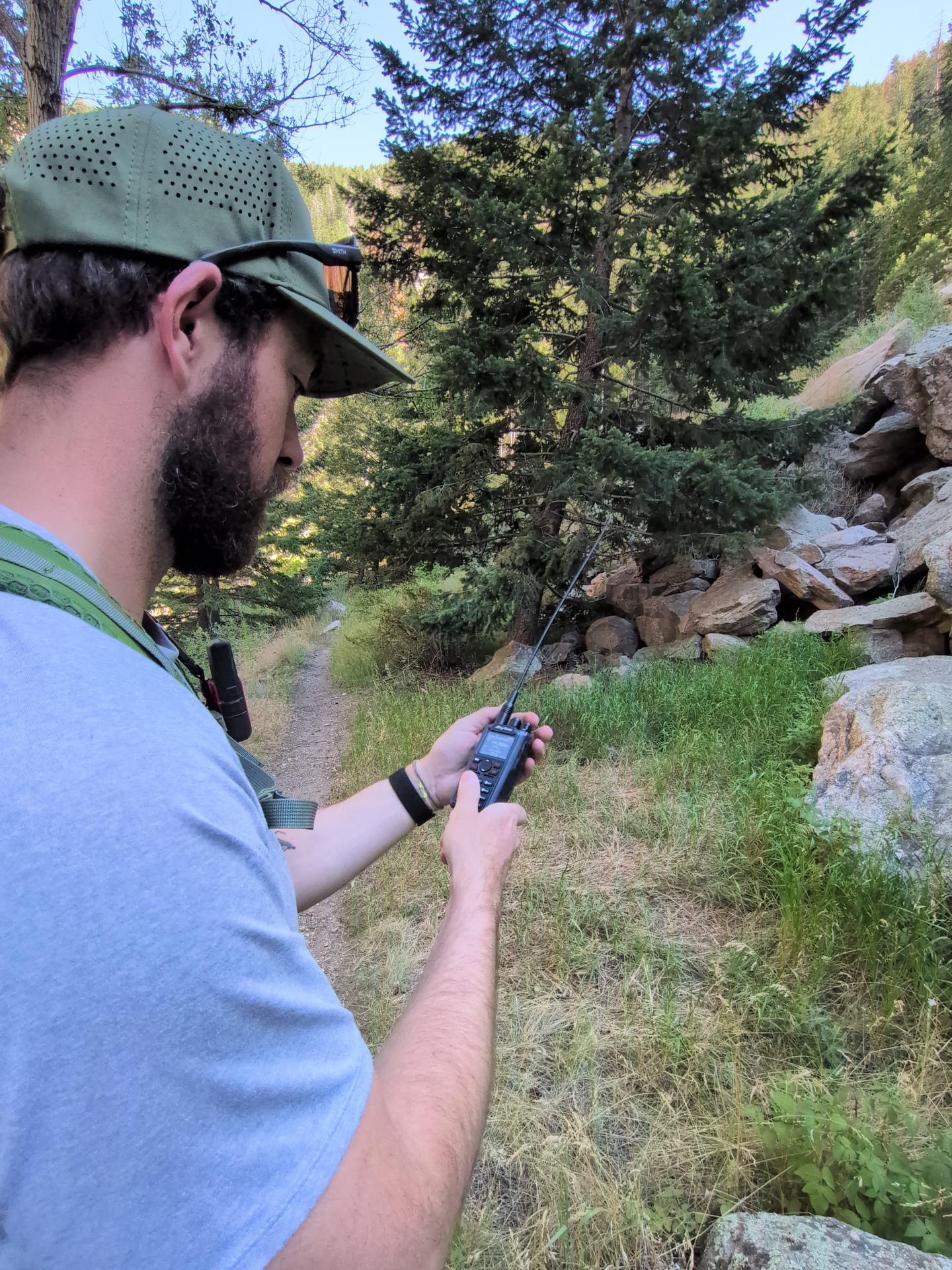 An AnyTone multi-band handheld radio being used during a backcountry trip.