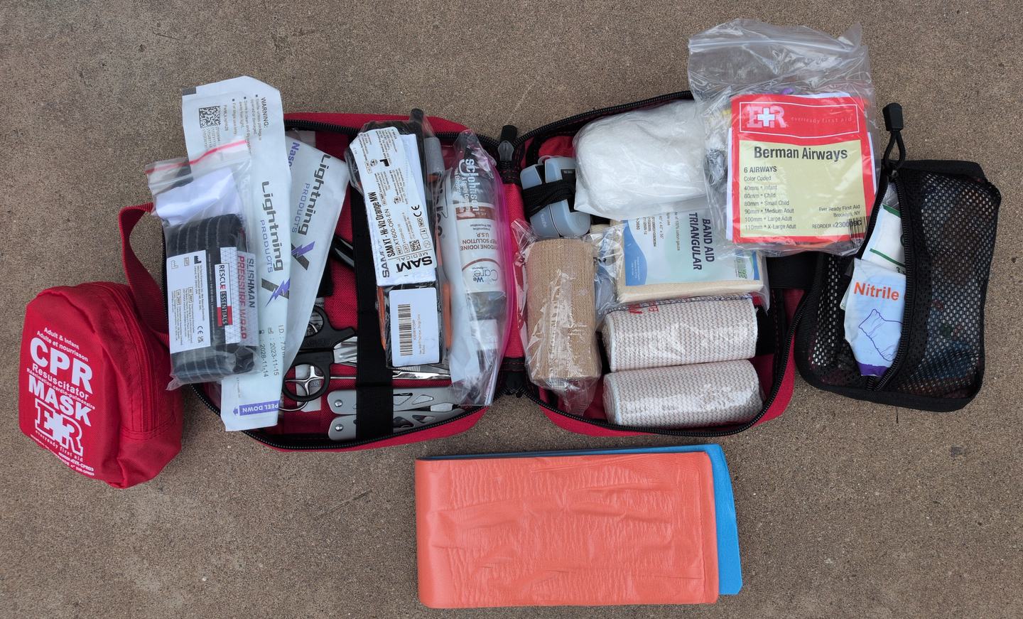 The full contents of a self-assembled backcountry medical kit laid out on the ground.