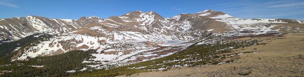 A snow-covered alpine basin under a clear sky, ringed by high mountain peaks