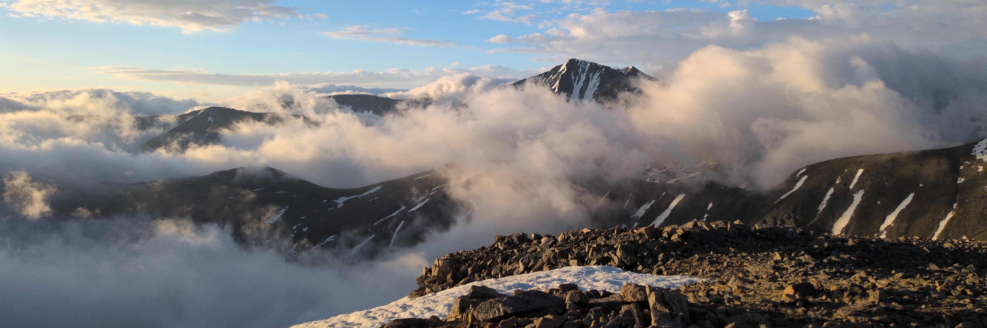 A cloudy morning over a mountain ridge with mountain peaks in the background